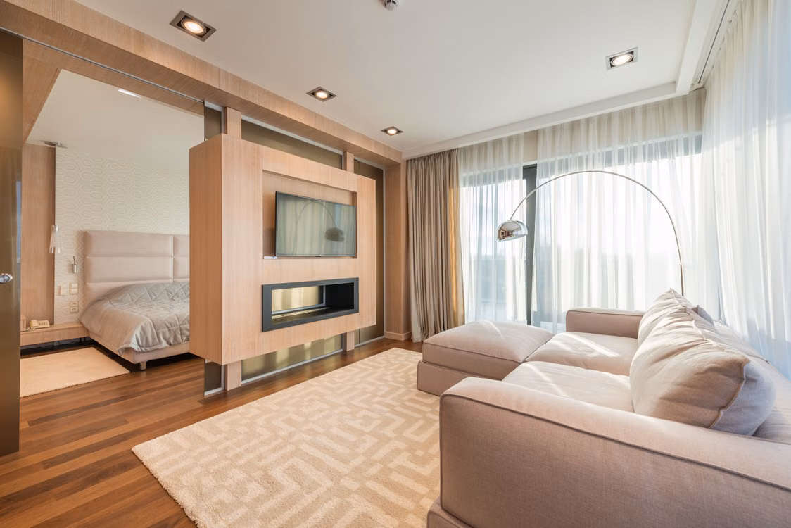Representative image: Interior of modern apartment with comfortable couch with pillows on carpet against TV in living room near bedroom with bed